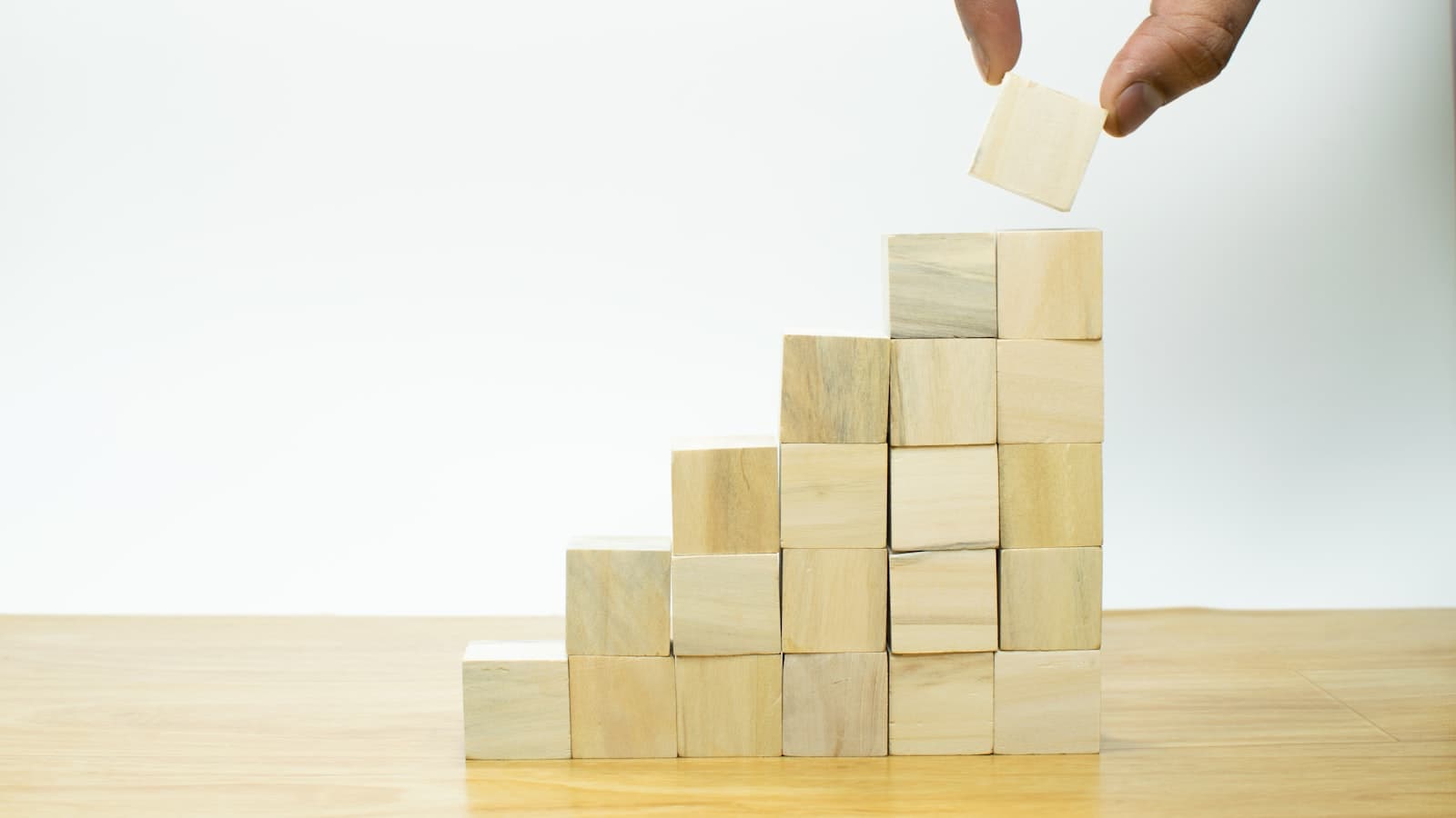 A person placing a piece of wood into a pyramid