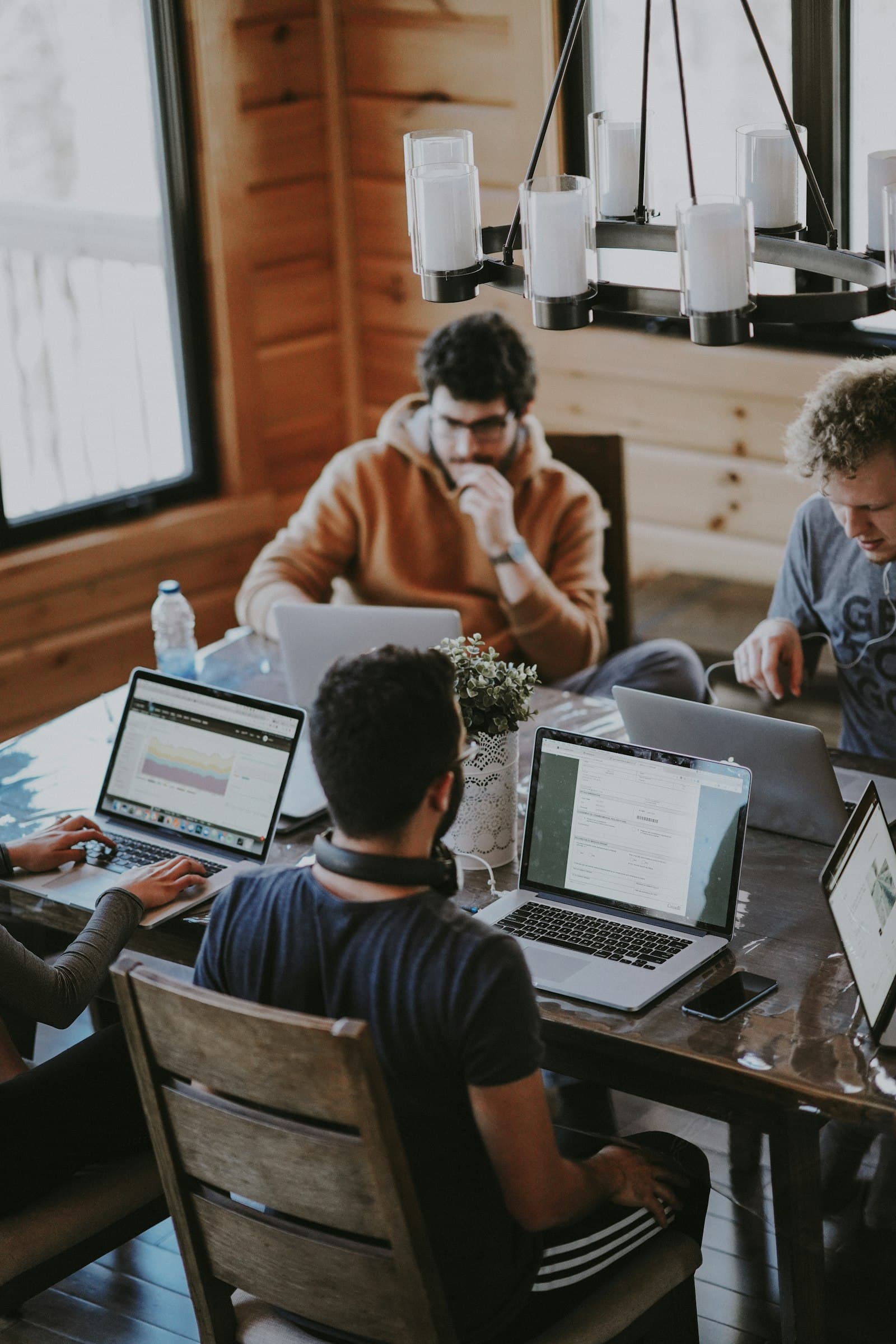 A team collaborating on laptops around a wooden table in a warm, sunlit room