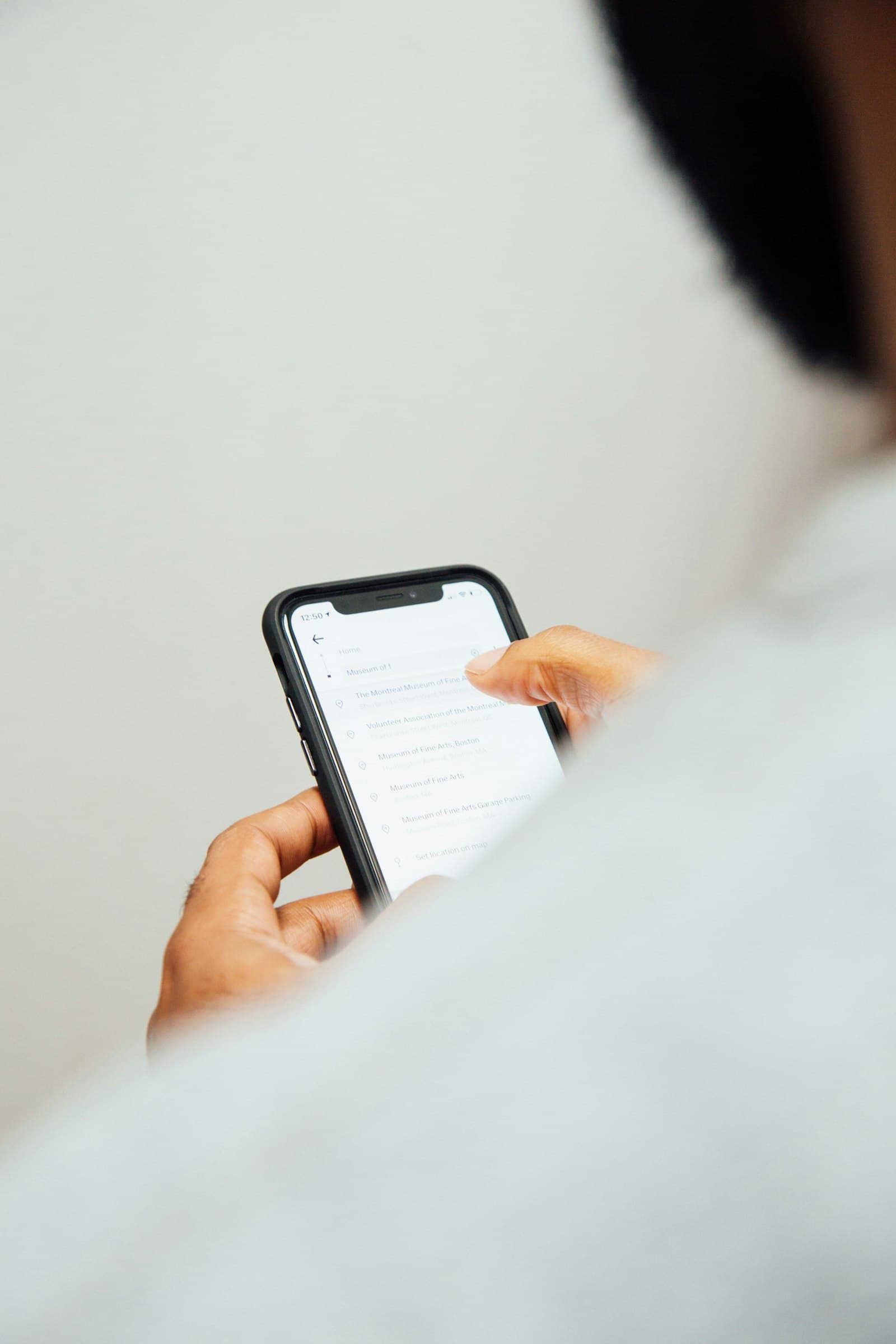 Hand holding a phone showing a list of search results